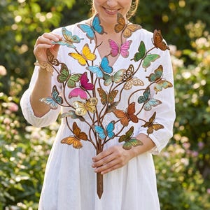 May include: A metal garden stake featuring a branching structure adorned with numerous butterflies in various colors including blue, yellow, pink, green, orange, and brown. The butterflies are arranged along thin, dark brown metal stems.