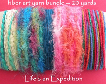 May include: A fiber art yarn bundle measuring 20 yards, featuring various textures and colors including turquoise, cream, blue, pink, and a multi-colored striped section. The text "fiber art yarn bundle -- 20 yards" and "Life's an Expedition" is visible.