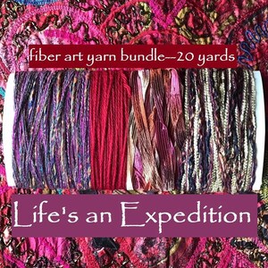 May include: A fiber art yarn bundle measuring 20 yards, featuring four distinct textures and colors including variegated purple, solid red, metallic copper ribbon, and a multi-tonal metallic blend. Text reads: fiber art yarn bundle--20 yards and Life's an Expedition.