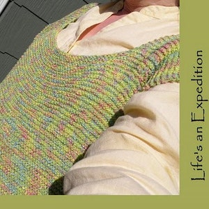 May include: A knitted sweater in shades of green, yellow, pink, and blue. The sweater has a scoop neck and long sleeves. The text "Life's an Expedition" is on the right side of the image.