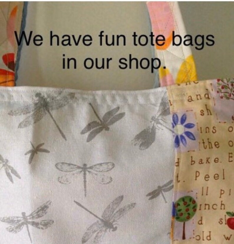 May include: A white tote bag with a dragonfly print. The bag has a patchwork design with a yellow, pink, and blue floral pattern. The text "We have fun tote bags in our shop." is printed on the bag.