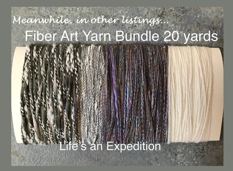 Puede incluir: Un paquete de cuatro ovillos de hilo, cada uno de 20 yardas de largo. Los ovillos son en tonos de gris, blanco y morado. El texto "Fiber Art Yarn Bundle 20 yards" y "Life's an Expedition" es visible en la etiqueta.