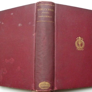 May include: A burgundy hardback book with gold lettering on the spine. The title is "Vanity Fair" by Thackeray. The book is part of the University Edition series.