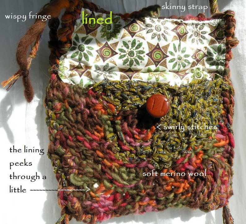 May include: A small, brown, green, and red knitted bag with a lined interior. The lining is a white fabric with a green and brown floral pattern. The bag has a skinny strap and a wispy fringe. The bag is made of soft merino wool and has a button closure.
