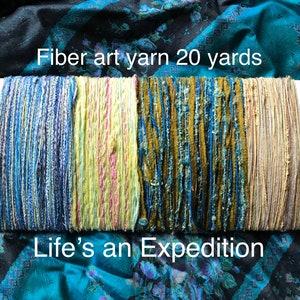 May include: Four skeins of fiber art yarn, each 20 yards long. The skeins are in shades of blue, yellow, green, and beige. The text "Fiber art yarn 20 yards" and "Life's an Expedition" is visible on the image.