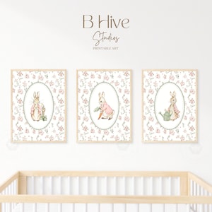 Puede incluir: Tres impresiones enmarcadas con ilustraciones de acuarela de conejos. Cada impresión tiene un fondo floral y un marco ovalado. Los conejos se representan en varias poses, sosteniendo una regadera, una zanahoria y una pala. El texto "B Hive Studios PRINTABLE ART" está en la parte superior.