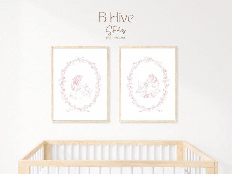May include: Two framed prints of a pink line drawing of a girl and a goat in a wreath of flowers. The prints are hanging on a white wall above a wooden crib.