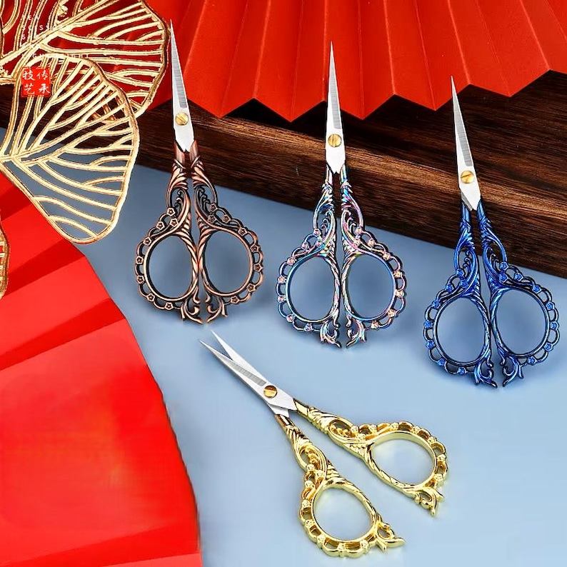 May include: Four pairs of decorative scissors with ornate handles. The scissors are in gold, bronze, blue, and iridescent colors.