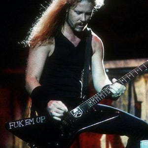 Puede incluir: Un músico con cabello largo y castaño claro toca una guitarra eléctrica negra. La guitarra tiene un emblema de calavera y las palabras "FUK EM UP". El músico viste una camiseta sin mangas negra y pantalones negros.