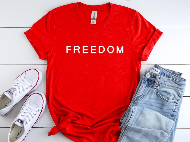 Red Gildan unisex t-shirt with bold white text reading FREEDOM, patriotic graphic shirt.

Charlie Kirk Freedom shirt in red with free speech message, unisex cotton blend tee.