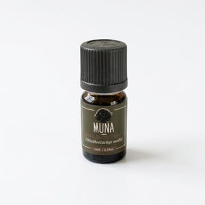 May include: A small, dark amber glass bottle of Muna natural oil with a black cap. The label is olive green with white text and a small illustration. The bottle contains 10ml / 0.34oz of oil.