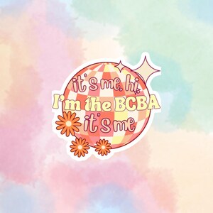 May include: A sticker with a disco ball design and the text "it's me, hi I'm the BCBA it's me". The disco ball is pink and yellow with a white checkered pattern. There are three orange flowers around the disco ball.