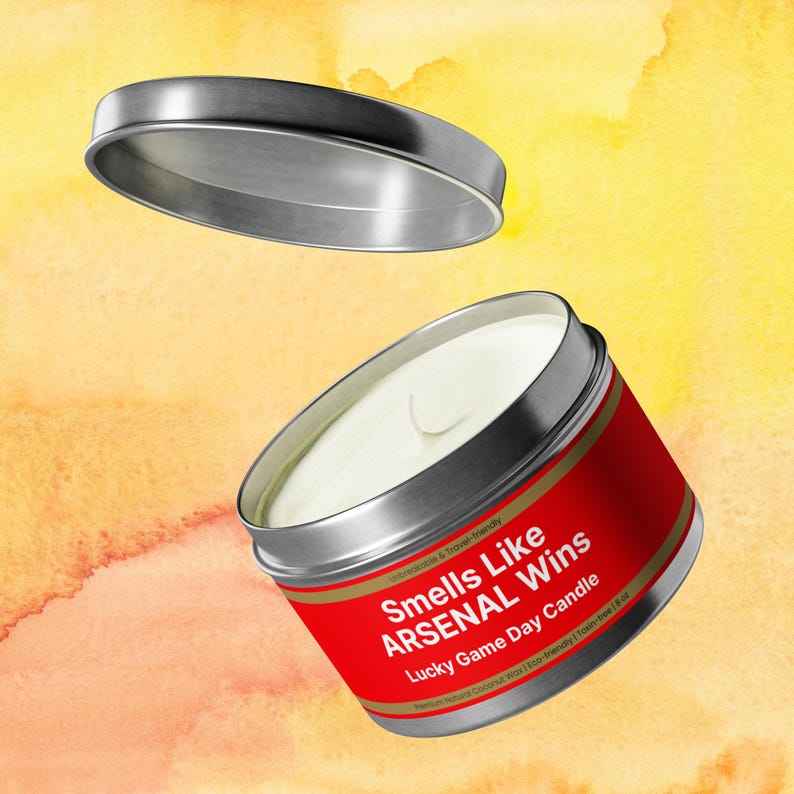 Wonderscape Wicks candle shop on Etsy presenting silver color 8 oz tin candle with text smells like Arsenal Wins Lucky Game Day Candle on a colorful background. The all natural cotton-wick candle can be personalized with customer's custom text. The design is aimed at Premier League Football Soccer fans with Arsenal red and white colors. Gift for wife boyfriend husband girlfriend brother sister Bukayo Saka Martin Odegaard Declan Rice Gabriel Martinelli Thierry Henry Dennis Bergkamp