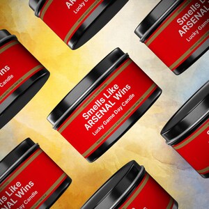 Wonderscape Wicks candle shop on Etsy presenting black color 8 oz tin candle collection with text smells like Arsenal Wins Lucky Game Day Candle on a colorful background. The all natural cotton-wick candle can be personalized with customer's custom text. The design is aimed at Premier League Football Soccer fans with Arsenal red and white colors. Gift for wife boyfriend husband girlfriend brother sister Bukayo Saka Martin Odegaard Declan Rice Gabriel Martinelli Thierry Henry Dennis Bergkamp