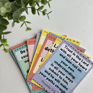 Puede incluir: Un conjunto de tarjetas coloridas con citas inspiradoras y vers&iacute;culos b&iacute;blicos. Las tarjetas son en tonos de rosa, amarillo, azul y verde, con texto negro. Las tarjetas est&aacute;n abanicadas, con una ramita de vegetaci&oacute;n en el fondo.