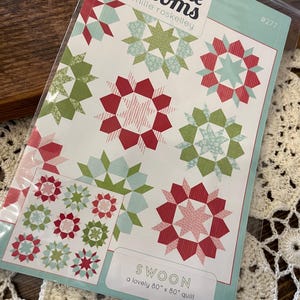 May include: A quilting pattern for a quilt called "Swoon" by Thimble Blossoms by Camille Roskelley. The pattern is for a 80" x 80" quilt and features a variety of red, green, and blue star-shaped blocks.