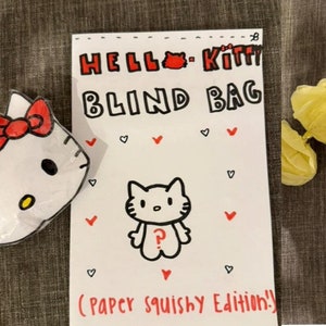 May include: A white paper bag with "HELLO KITTY BLIND BAG" in red and black lettering, featuring a Hello Kitty illustration and the text "(PAPER SQUISHY EDITION!!)". A separate paper shows rarity levels with Hello Kitty bow illustrations.