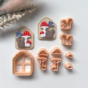 May include: A collection of light orange cookie cutters in various shapes. The shapes include a house, mushrooms, squirrels, and mushroom-shaped cutouts. Some cutters have detailed designs of mushrooms and squirrels.