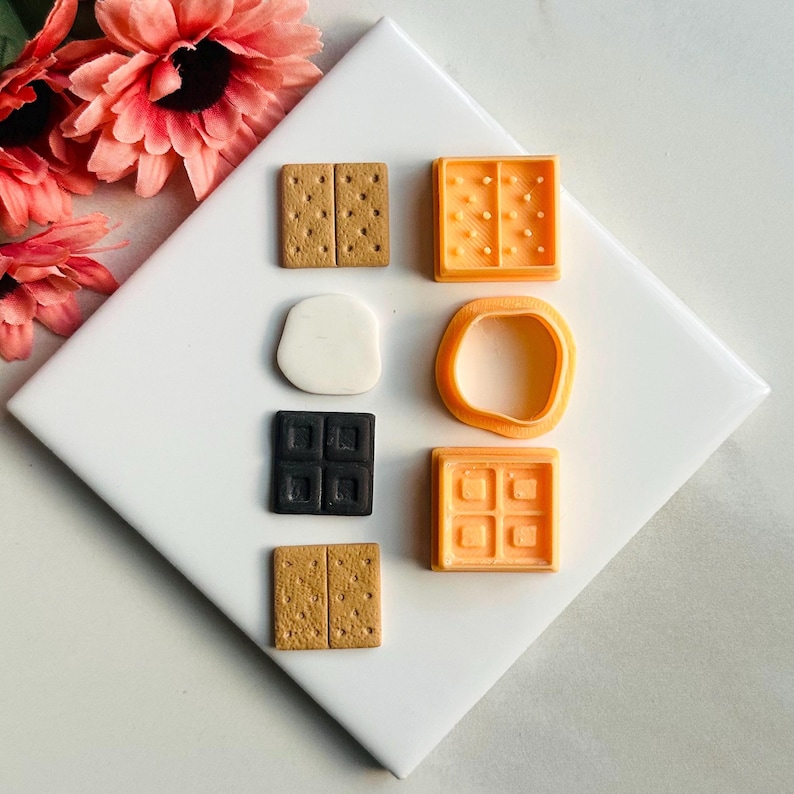 K&ouml;nnte beinhalten: Ein Set mit sechs Miniatur-Zutaten f&uuml;r S'mores, darunter Graham-Cracker, Schokoladenquadrate und Marshmallows. Die Artikel sind aus Polymer Clay gefertigt und perfekt zum Basteln oder Dekorieren.