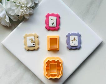 Può includere: Quattro diversi tagliapasta a forma di cornice, due rosa, uno viola e uno giallo. I tagliapasta sono su una superficie bianca.