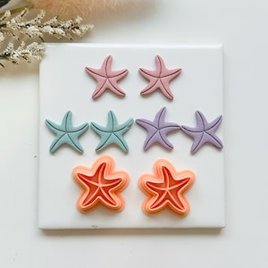 May include: A selection of starfish-shaped craft supplies in shades of pink, blue, purple, and orange. The starfish are arranged on a white surface, ideal for crafting or seaside-themed decorations. Each starfish is approximately 5 cm in diameter.