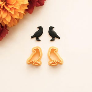 Può includere: Due figure a forma di corvo nero e due stampini per biscotti a forma di corvo color arancione chiaro. Le figure nere sono solide e dettagliate, mentre gli stampini arancioni hanno un bordo rialzato per ritagliare le forme.