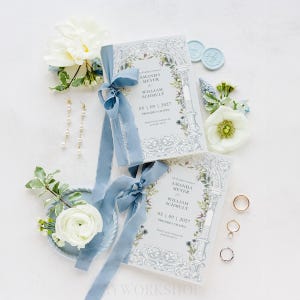 May include: Wedding ceremony programs with blue ribbons, floral accents, and the names Amanda Meyer and William Schmutt. The date is 05/09/2027. Also, there are gold rings, pearl earrings, and white flowers.