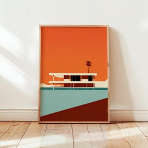 Könnte beinhalten: Gerahmter Kunstdruck mit einer Illustration eines Hauses der Moderne aus der Mitte des Jahrhunderts. Das Kunstwerk zeigt ein weißes Gebäude mit Flachdach vor einem orangefarbenen Himmel und einer blau-braunen Landschaft. Eine Palmensilhouette sorgt für einen tropischen Touch.
