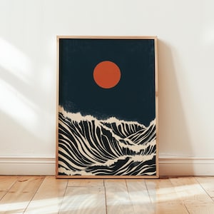 Könnte beinhalten: Ein gerahmter Kunstdruck mit einer minimalistischen Landschaft. Das Kunstwerk zeigt einen dunkelblauen Himmel mit einer großen orangefarbenen Sonne und stilisierten Wellen in Schwarz und Off-White. Der Druck ist in einem Naturholzrahmen.