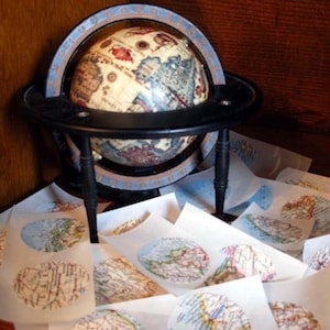 May include: A vintage globe with a black metal stand and a world map printed on it. The globe is surrounded by several white paper circles with maps printed on them.