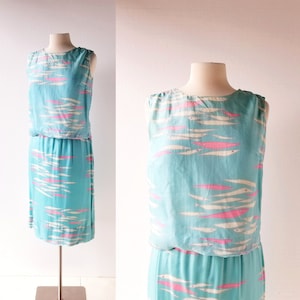 May include: A sleeveless dress with a turquoise blue background and a white and pink fish pattern. The dress has a fitted bodice and a slightly flared skirt.