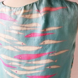 May include: A sleeveless dress with a teal blue background and a pattern of white and pink fish.