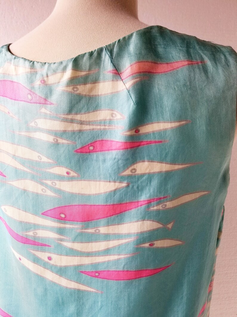 May include: A sleeveless dress with a teal blue background and a pattern of white and pink fish.