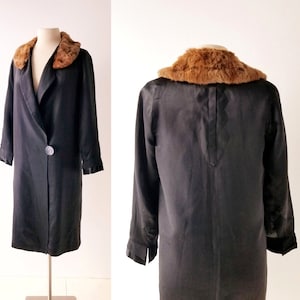 May include: A black satin coat with a brown fur collar. The coat has a single button fastening and long sleeves.