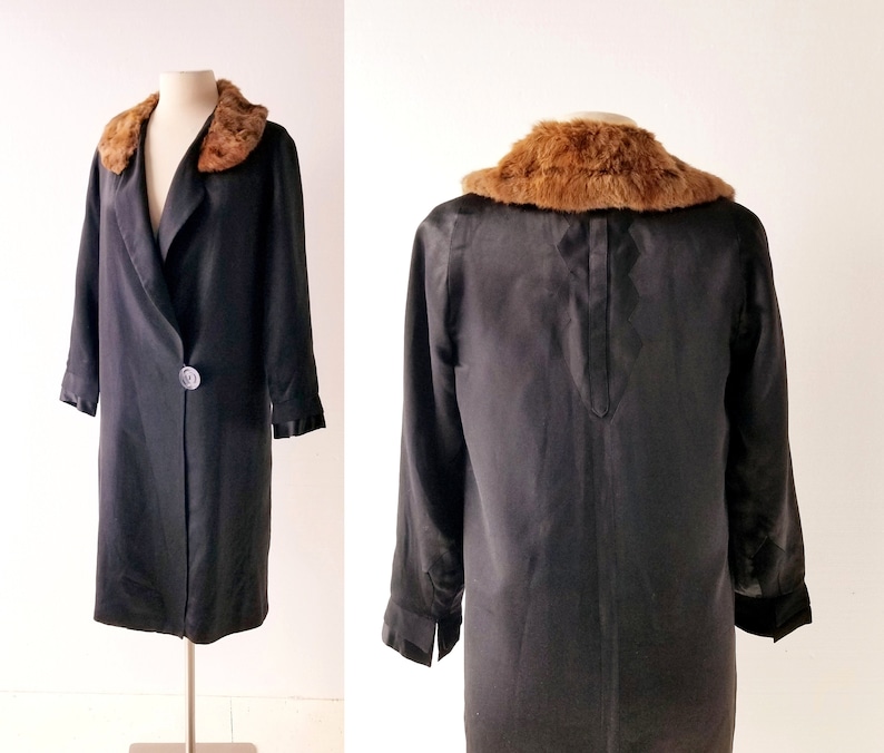 May include: A black satin coat with a brown fur collar. The coat has a single button fastening and long sleeves.