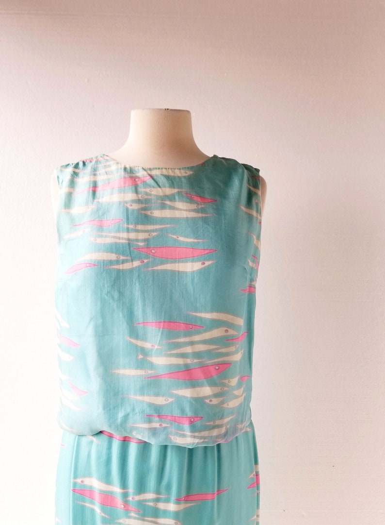 May include: A sleeveless maxi dress with a blue background and a pattern of pink and white fish.