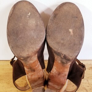 May include: A pair of brown suede heeled sandals with ankle straps. The soles are worn and show signs of use.