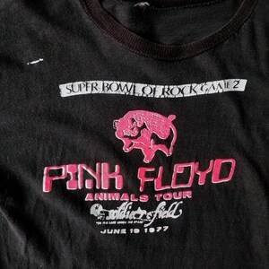 K&ouml;nnte beinhalten: Schwarzes T-Shirt mit einem rosa Schweine-Motiv und dem Text "Pink Floyd Animals Tour Soldier Field June 19 1977".