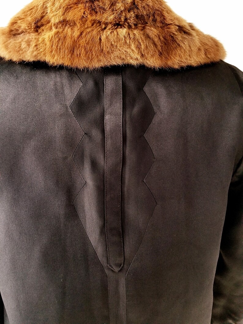 May include: Black satin jacket with a brown fur collar. The jacket features a distinctive diamond-shaped design on the back.