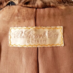 May include: A brown fur coat with a label that reads "R. Siegel Co. Detroit" in gold stitching.
