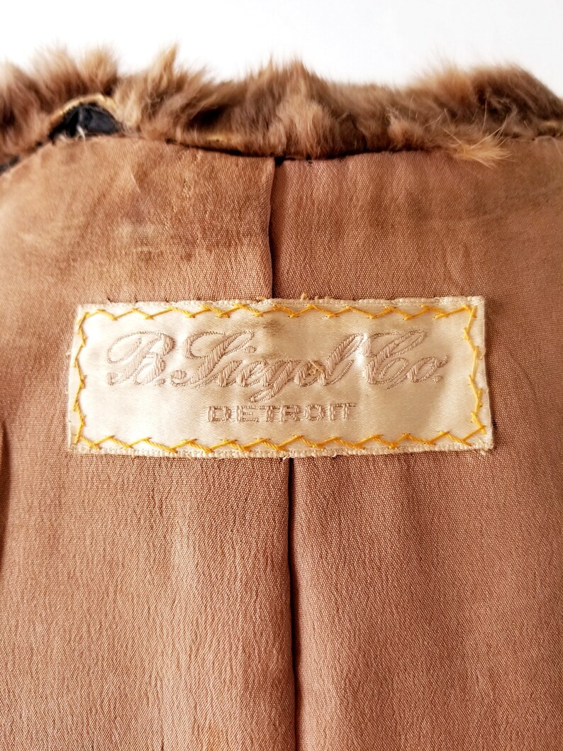 May include: A brown fur coat with a label that reads "R. Siegel Co. Detroit" in gold stitching.