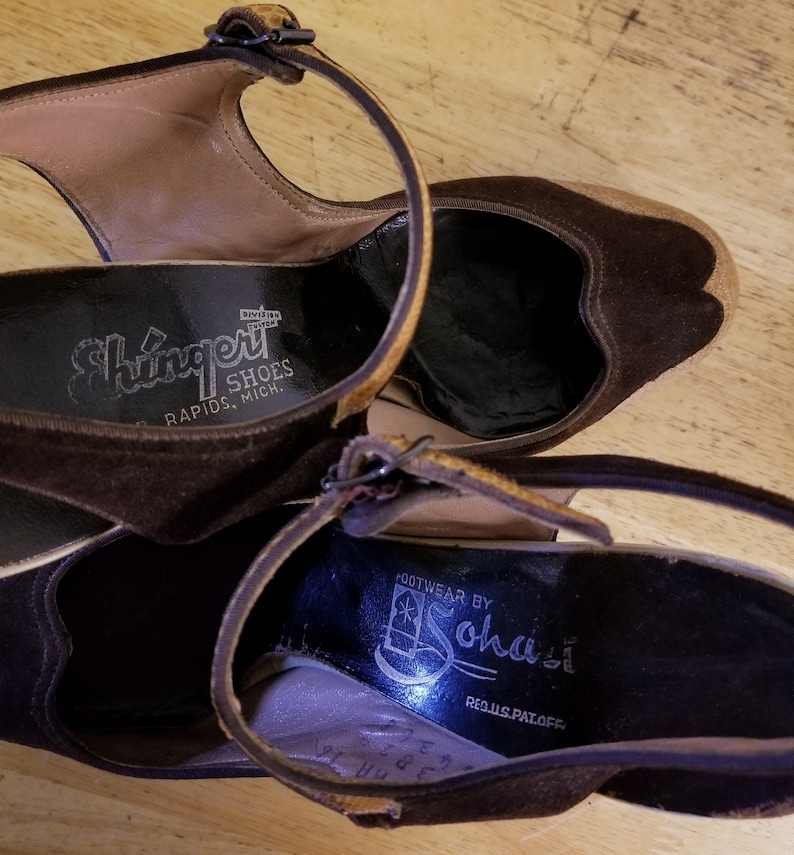 May include: A pair of brown suede heeled shoes with ankle straps. The shoes have a black leather insole with the text "Shingert Shoes Rapids, Mich." on one shoe and "Footwear by Sohasl Reg.U.S.Pat.Off." on the other shoe.