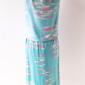 May include: A sleeveless dress with a blue background and a pink and white fish pattern. The dress is on a white mannequin.