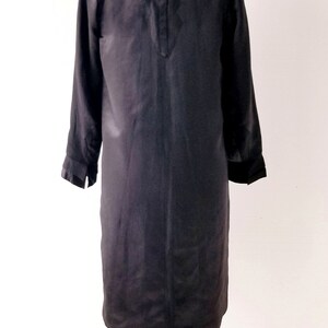 May include: A black satin dress with a brown fur collar. The dress is on a mannequin and has long sleeves.