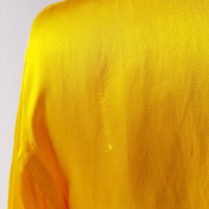 Puede incluir: Una tela de sat&eacute;n amarillo brillante con una textura suave.