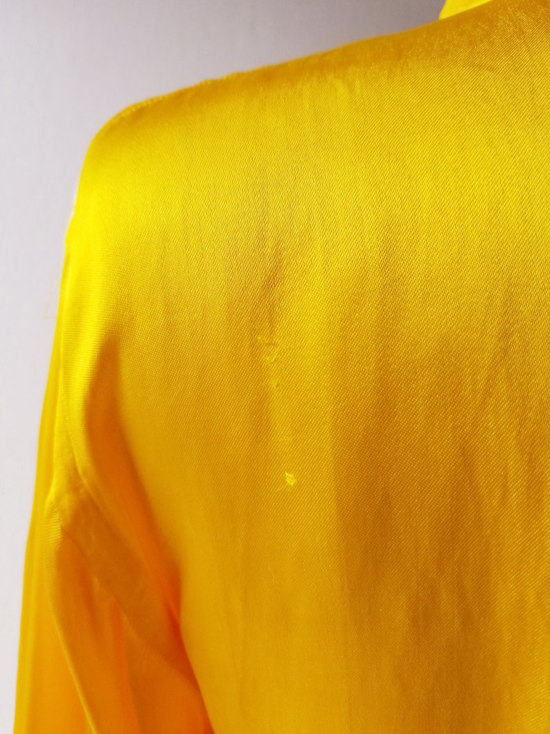 Puede incluir: Una tela de sat&eacute;n amarillo brillante con una textura suave.
