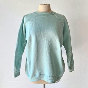 A vintage light mint green, crew neck, long sleeve pullover sweatshirt.