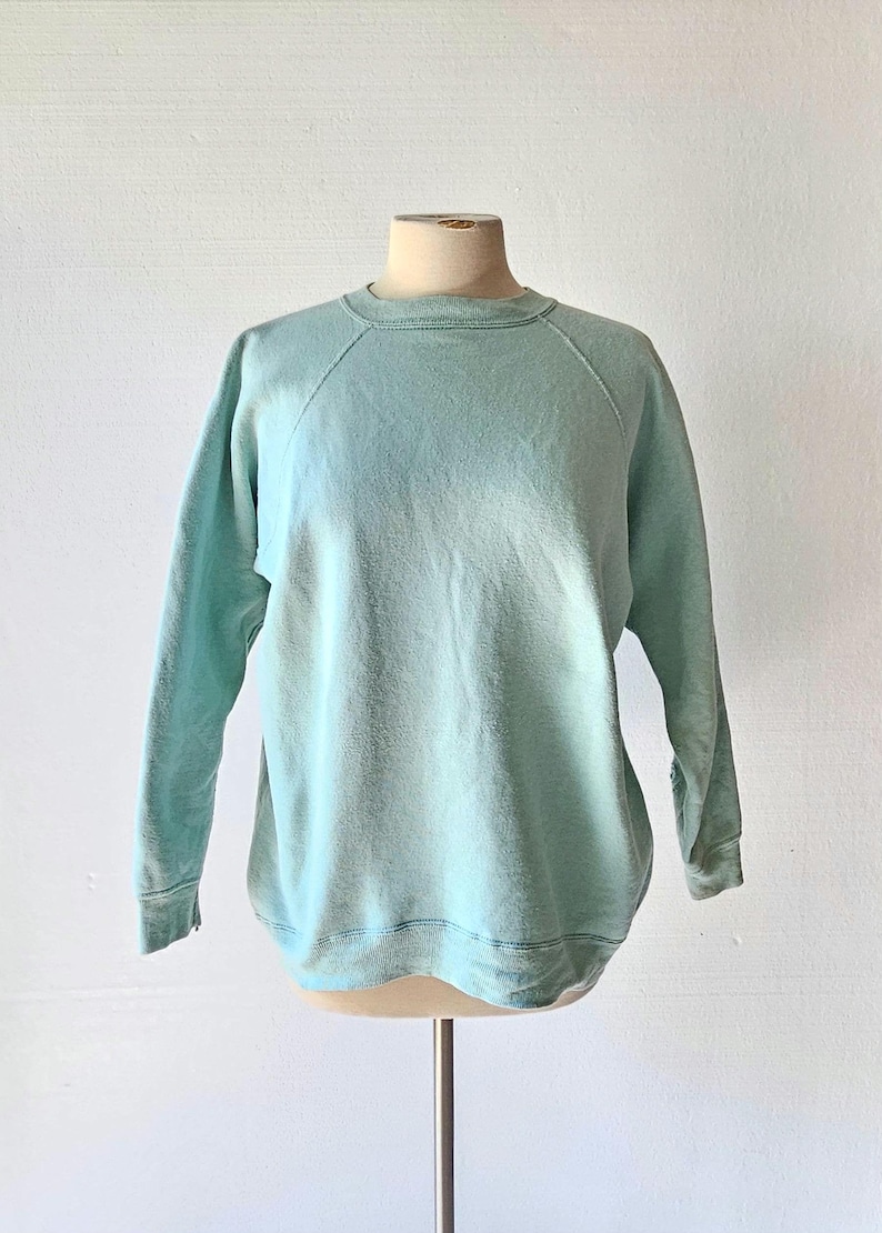 A vintage light mint green, crew neck, long sleeve pullover sweatshirt.