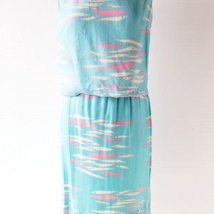 May include: A sleeveless dress with a blue background and a white and pink fish pattern. The dress has a fitted bodice and a flowing skirt.