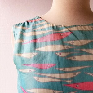 May include: A sleeveless dress with a turquoise background and a pattern of white and pink fish.